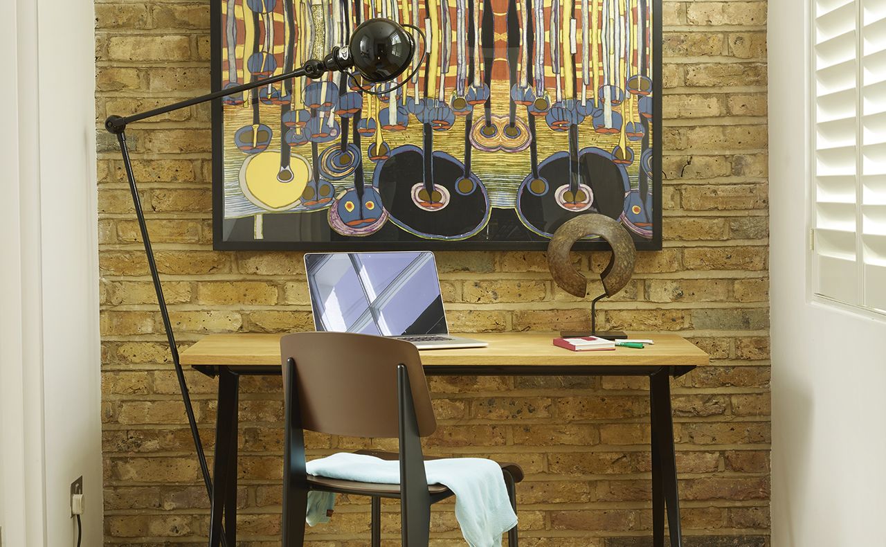 laptop on a desk in front of a bare brick wall