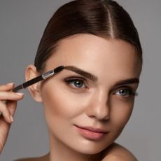 Model using spoolie on brows - getty 947018440 - eyebrow tinting kits