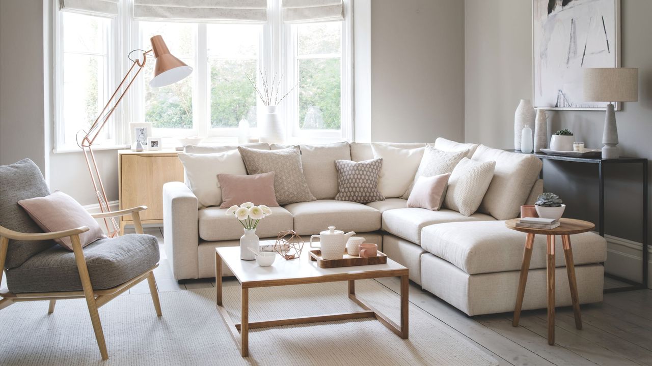 Beige living room with cream modular sofa and a grey accent chair, with a wooden coffee table in front