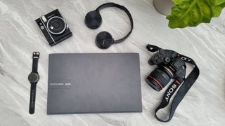 back to school supplies; a camera, laptop, smartwatch, and headphones on a marble desk