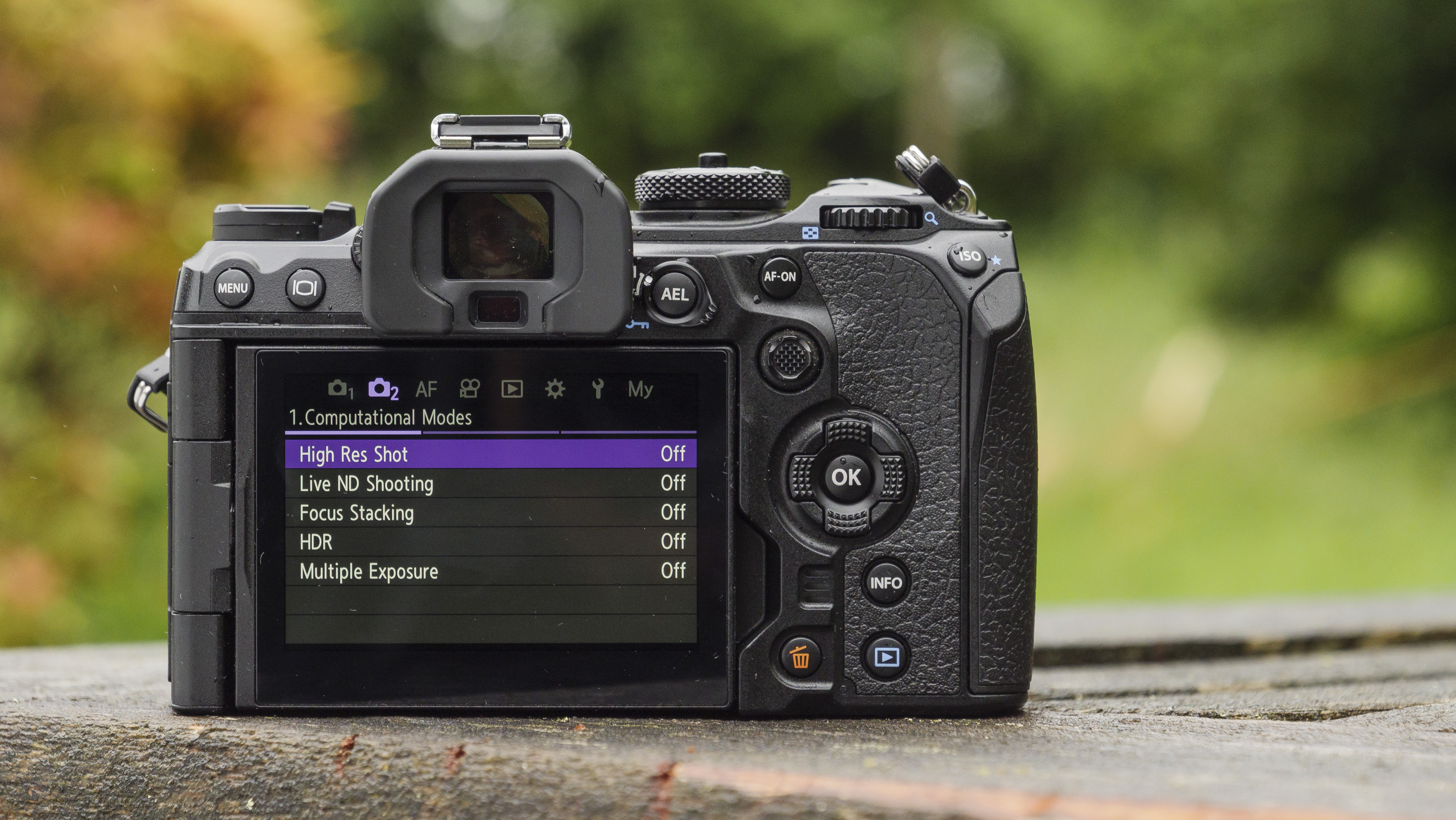 The rear screen of the OM System OM-1 camera sat on a wooden table