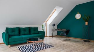 A home office in the loft with a green sofa and green accent wall