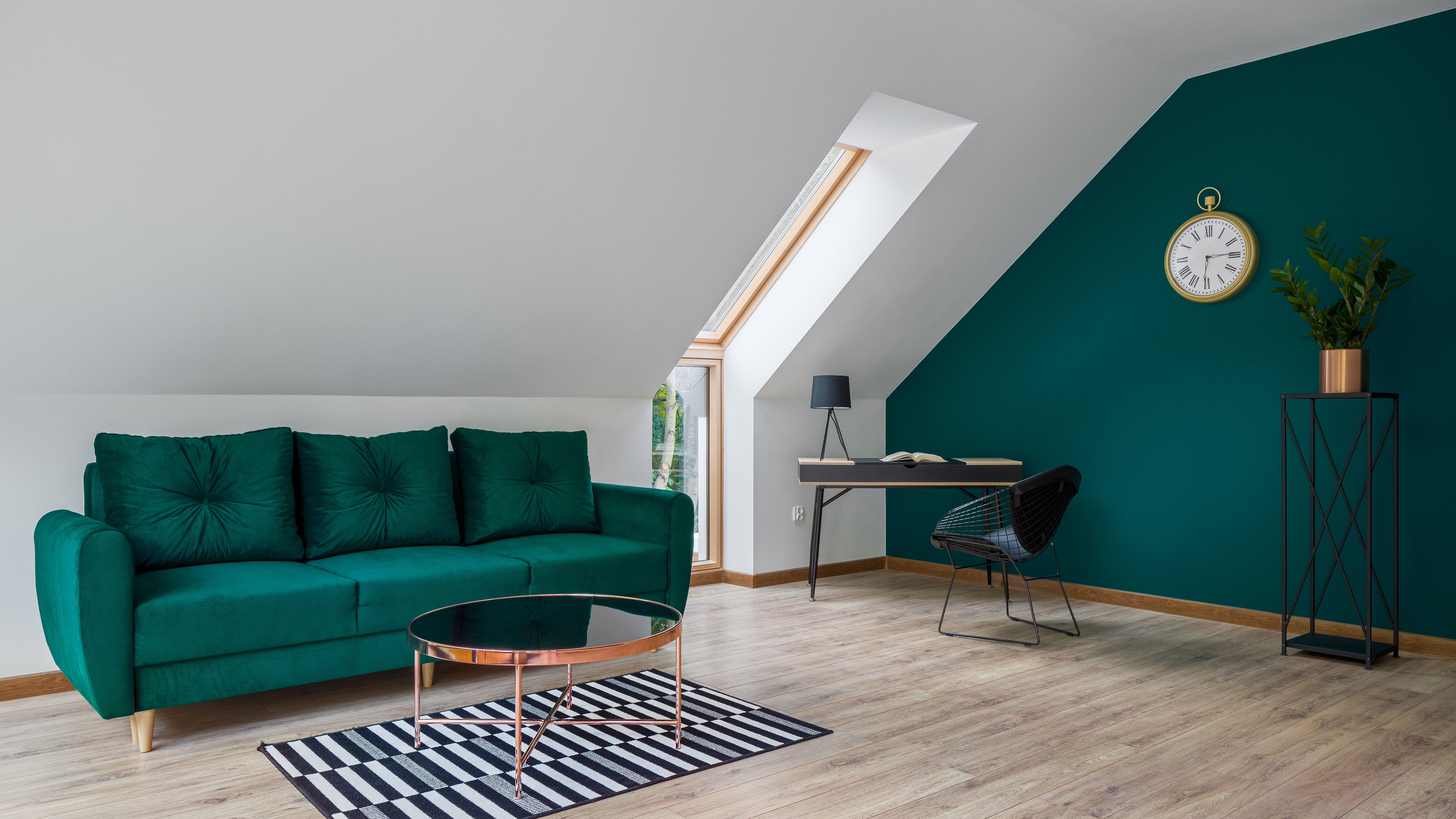 Escritório doméstico no sótão com um sofá verde e uma parede verde