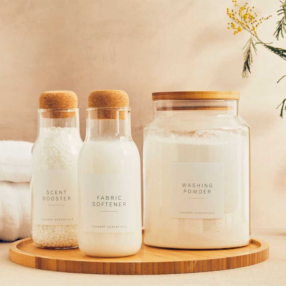 glass jars filled with laundry products to show how to organise under a kitchen sink