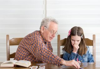 An older man plays a game with his grandaughter.
