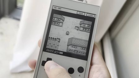 A hand taps the emulated d-pad of an original Game Boy on an ereader device. Pokemon Blue is being played in greyscale.