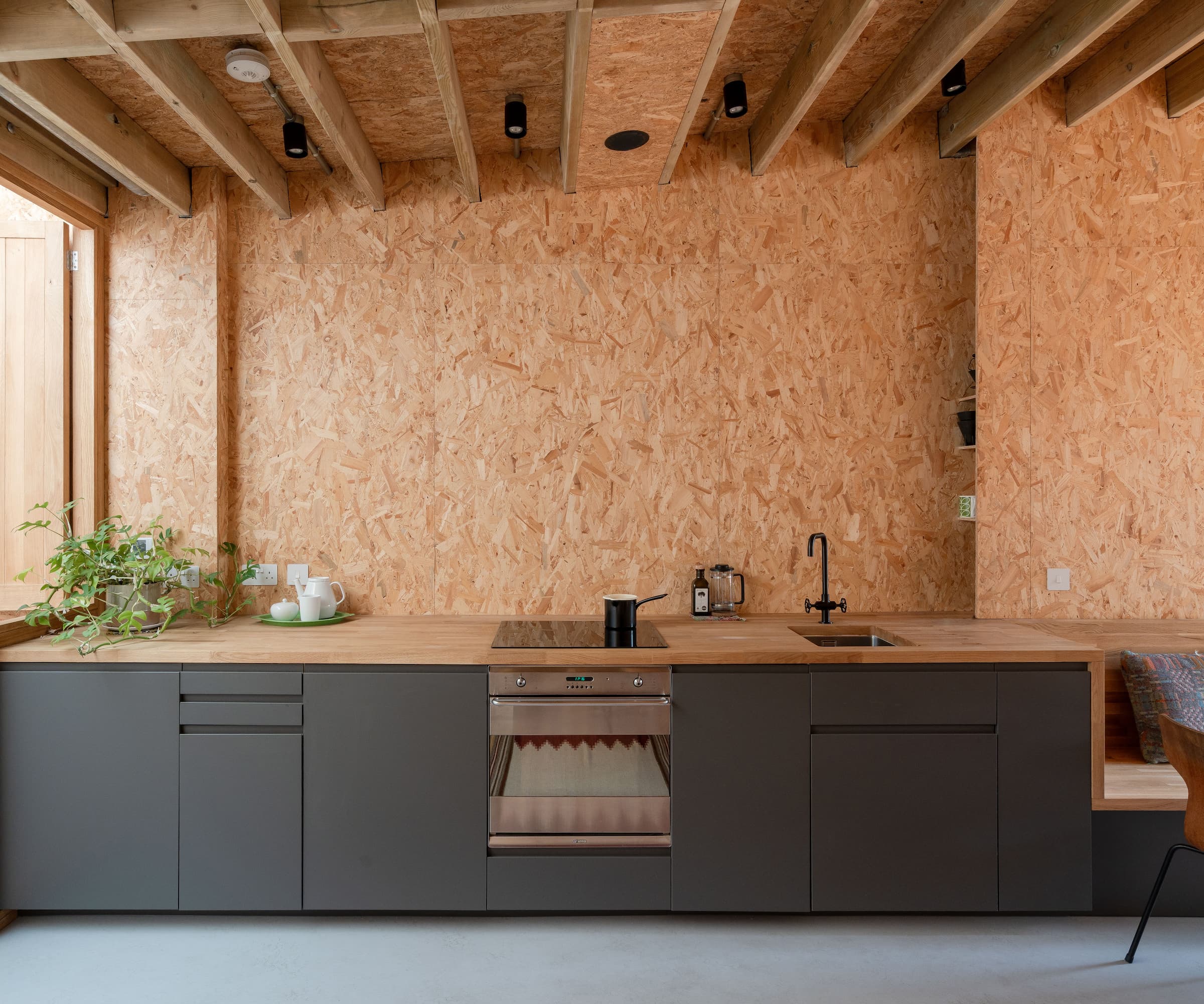 A kitchen with a plasterboard wall and a workstation with black cupboards and an induction hub