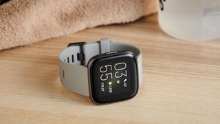 En billig smartklokke av typen Fitbit Versa 2 på et bord.