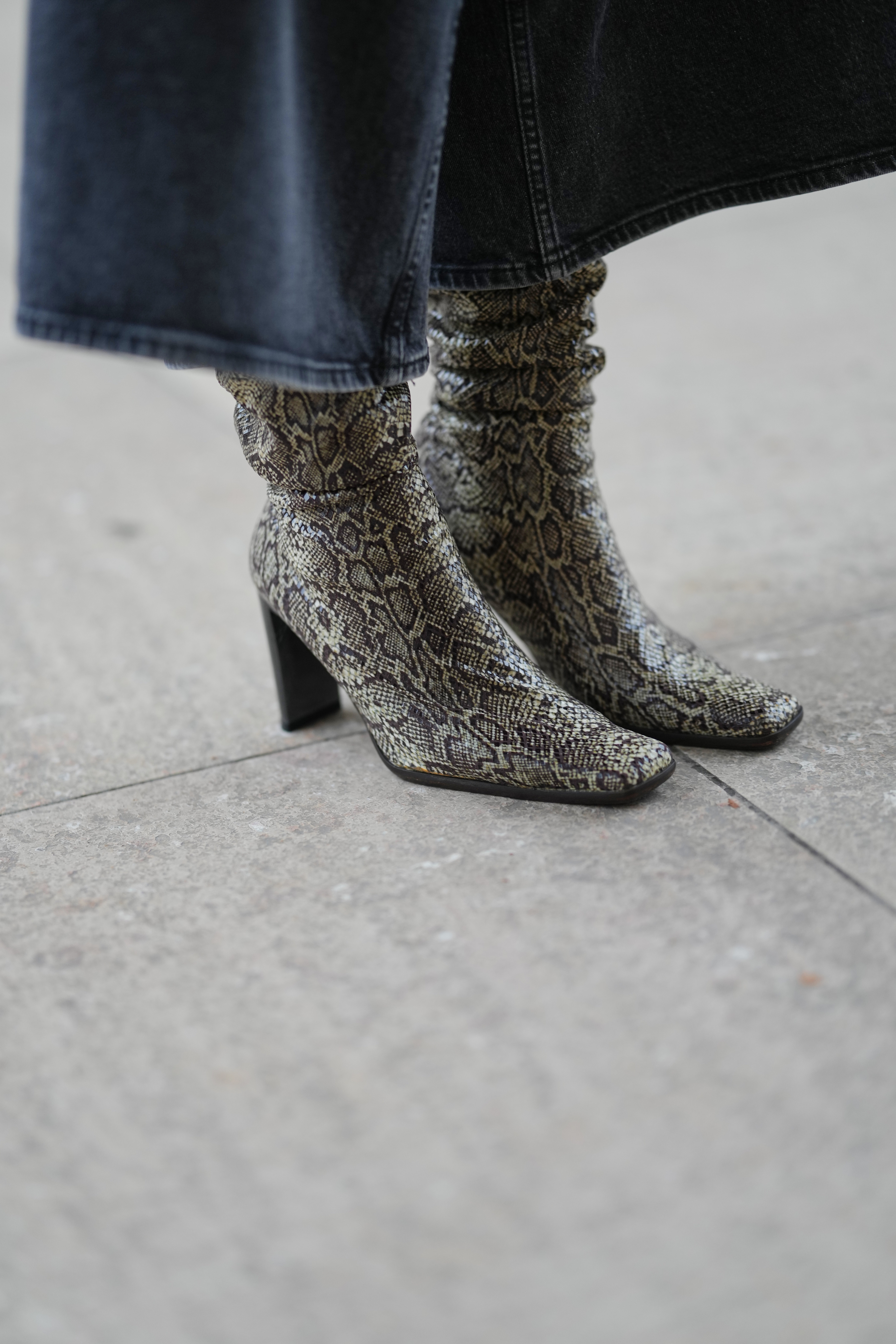 PARIS, FRANCE - DECEMBER 13: Close-up detail view of square tor pointed high heels boots with khaki snake print pattern, during a street style fashion photo session, on December 13, 2025 in Paris, France. (Photo by Edward Berthelot/Getty Images)
