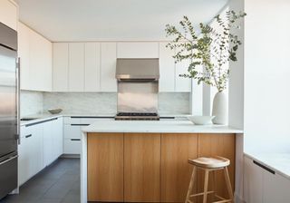 A white kitchen with wood, marble and stainless steel elements