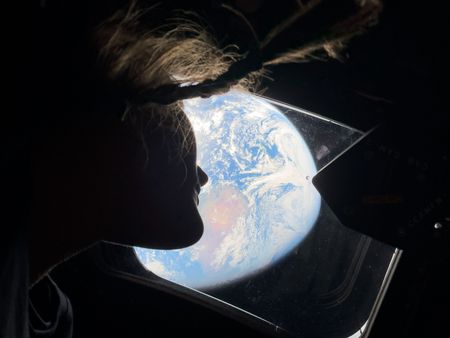 Mission Specialist Christina Koch looks out the window of Orion back to Earth