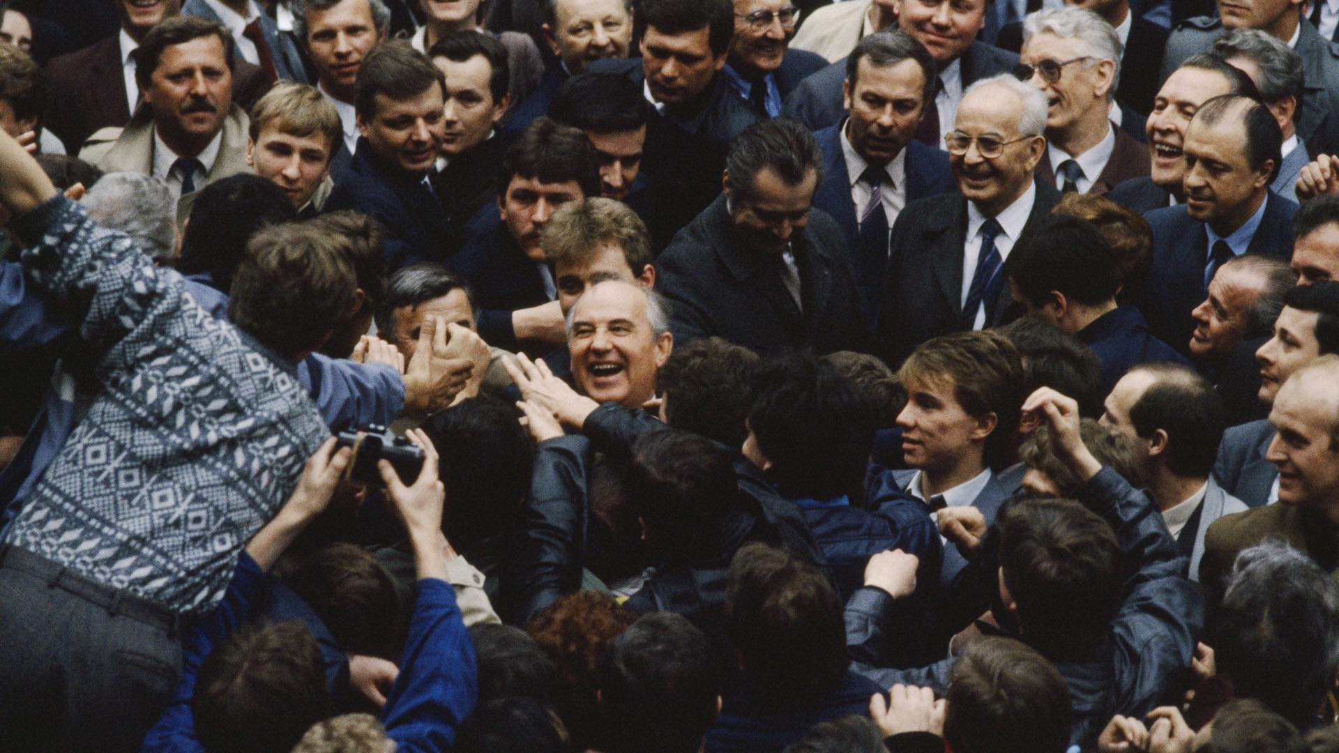 Soviet leader Mikhail Gorbachev (centre) laughs as he greets supporters during a visit to Prague, Czechoslovakia, 9th April 1987. Czechoslovakian President Gustav Husak watches with amusement.