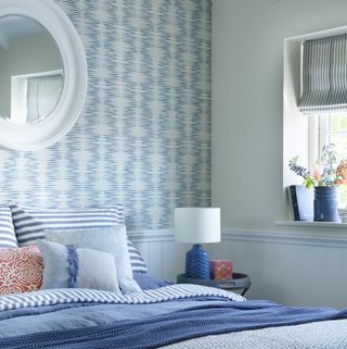 Bedroom with wallpaper, wall panels and mirror above bed