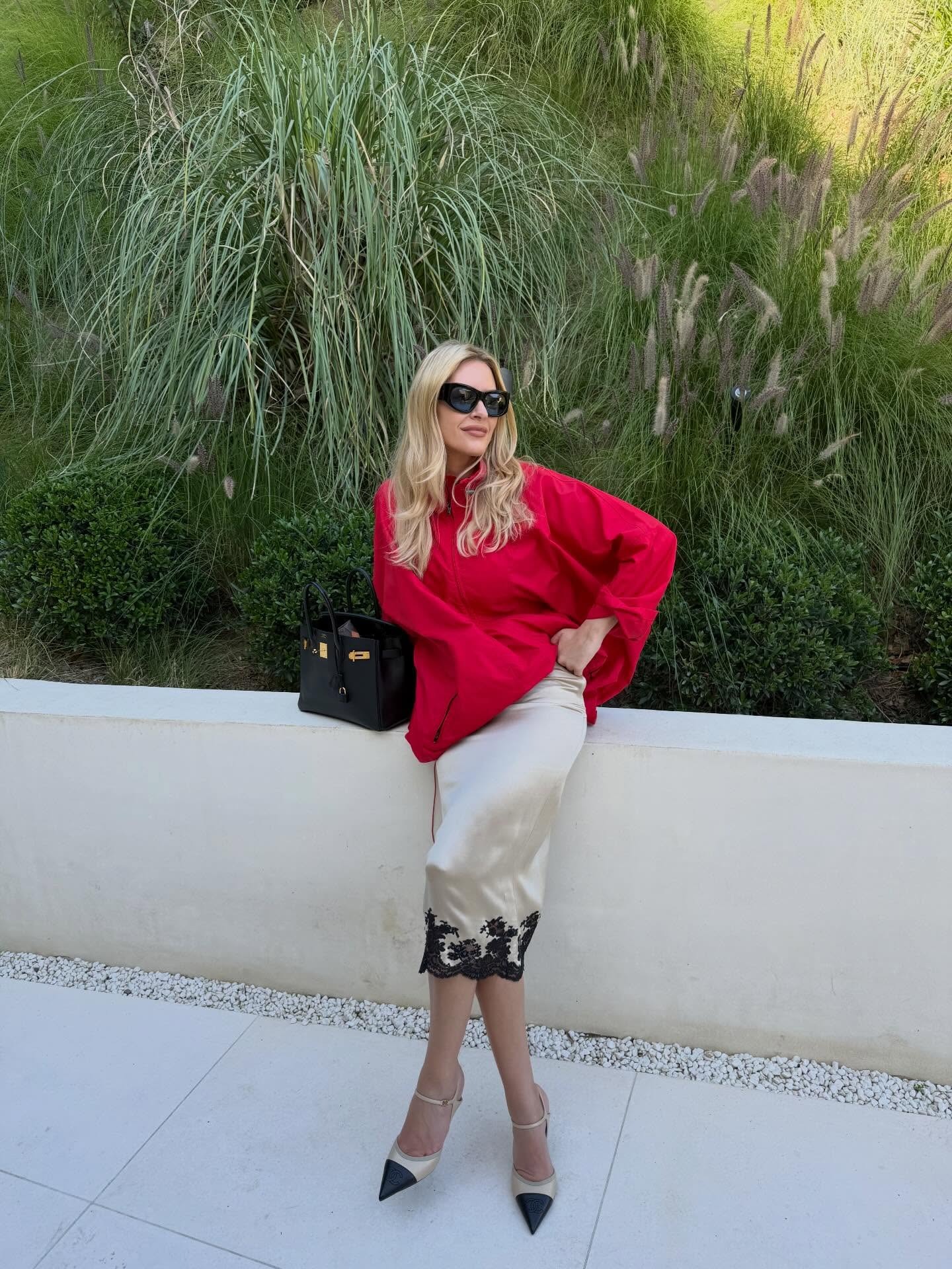 Morgan Stewart wearing a red windbreakers, lace-trim slip skirt, and cap-toe pumps