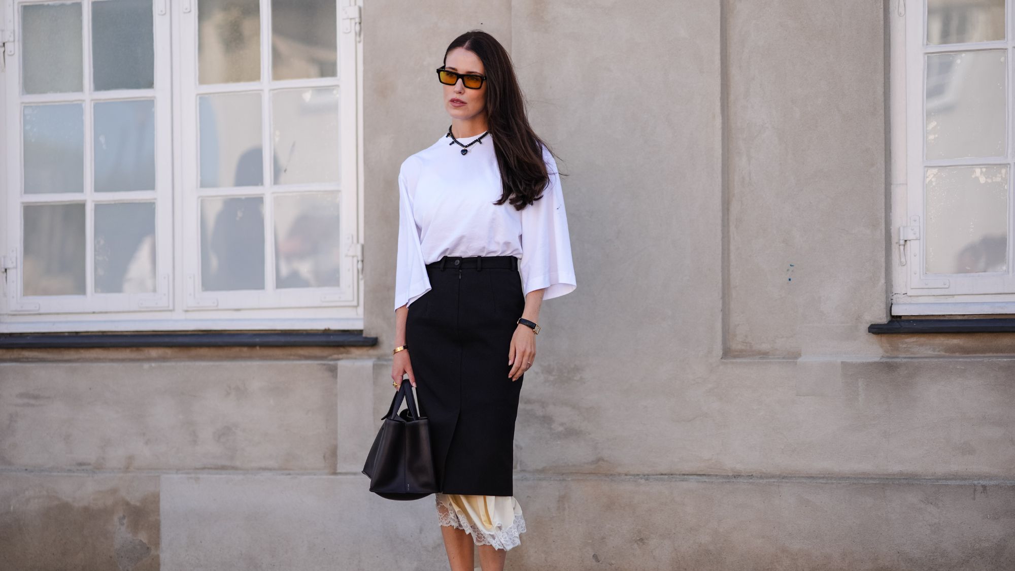 street style shot of woman wearing white t shirt and black skirt