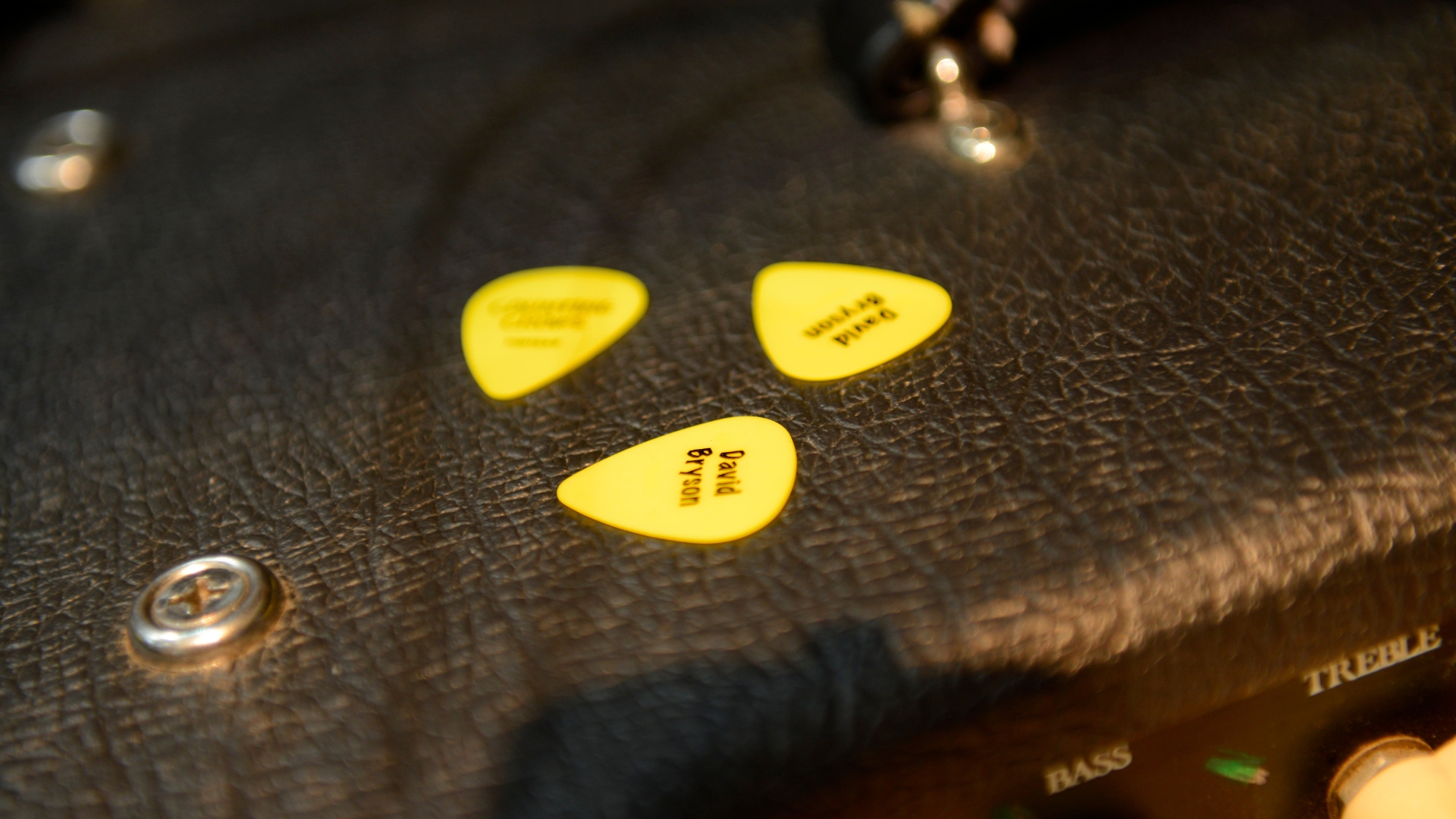 Three yellow guitar picks on top of an amplifier