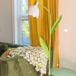 A DIY flower-shaped floor lamp in a living room next to a green velvet sofa