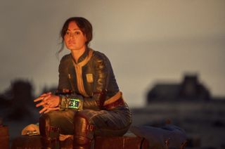 Amazon Fallout; a woman sits by a fire in the desert
