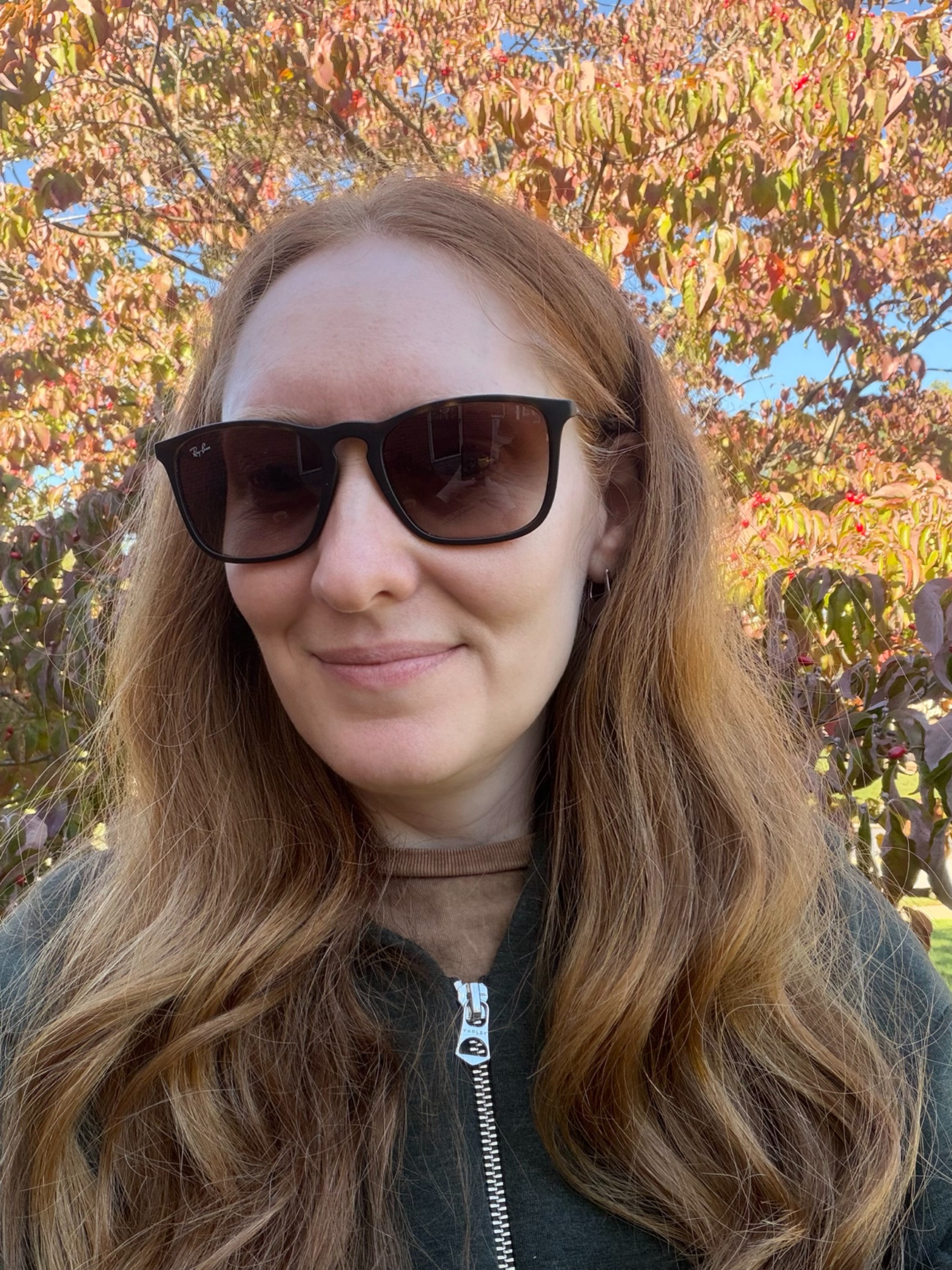 Kristin Contino wearing sunglasses standing in front of a tree