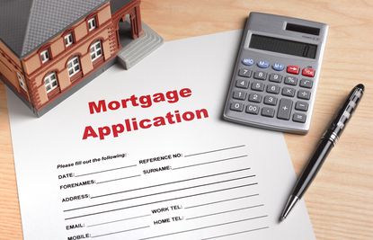 Mortgage application paperwork with calculator and model house