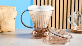 the clever dripper, a brown transparent plastic manual coffee maker with a handle and a sluice feature in the bottom to keep water inside