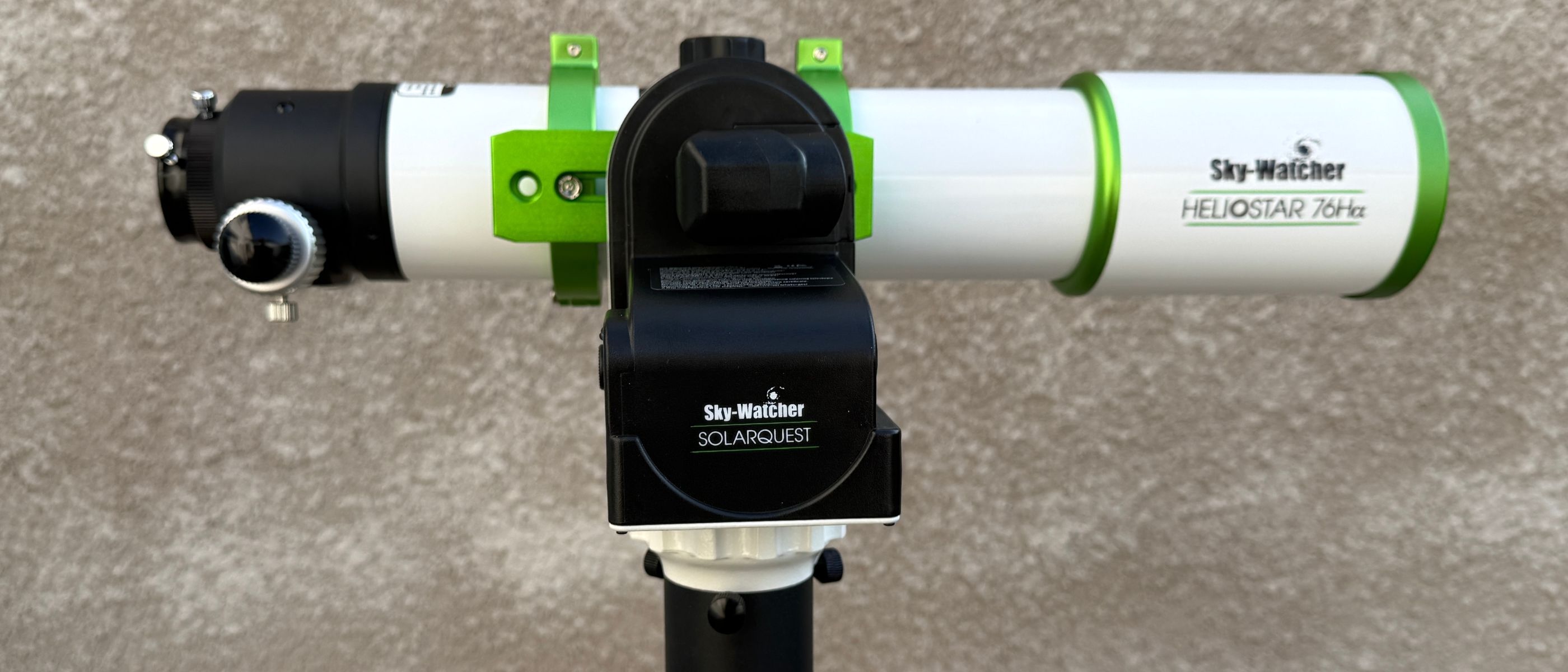 The Sky-Watcher Heliostar 76mm solar telescope attached to the Sky-Watcher SolarQuest solar telescope mount, against a textured grey wall.