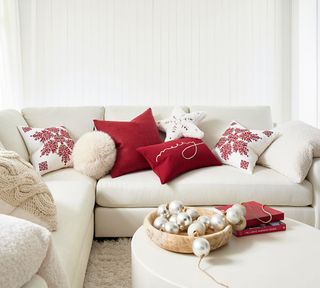 White couch dressed with red holiday pillows with festive signage