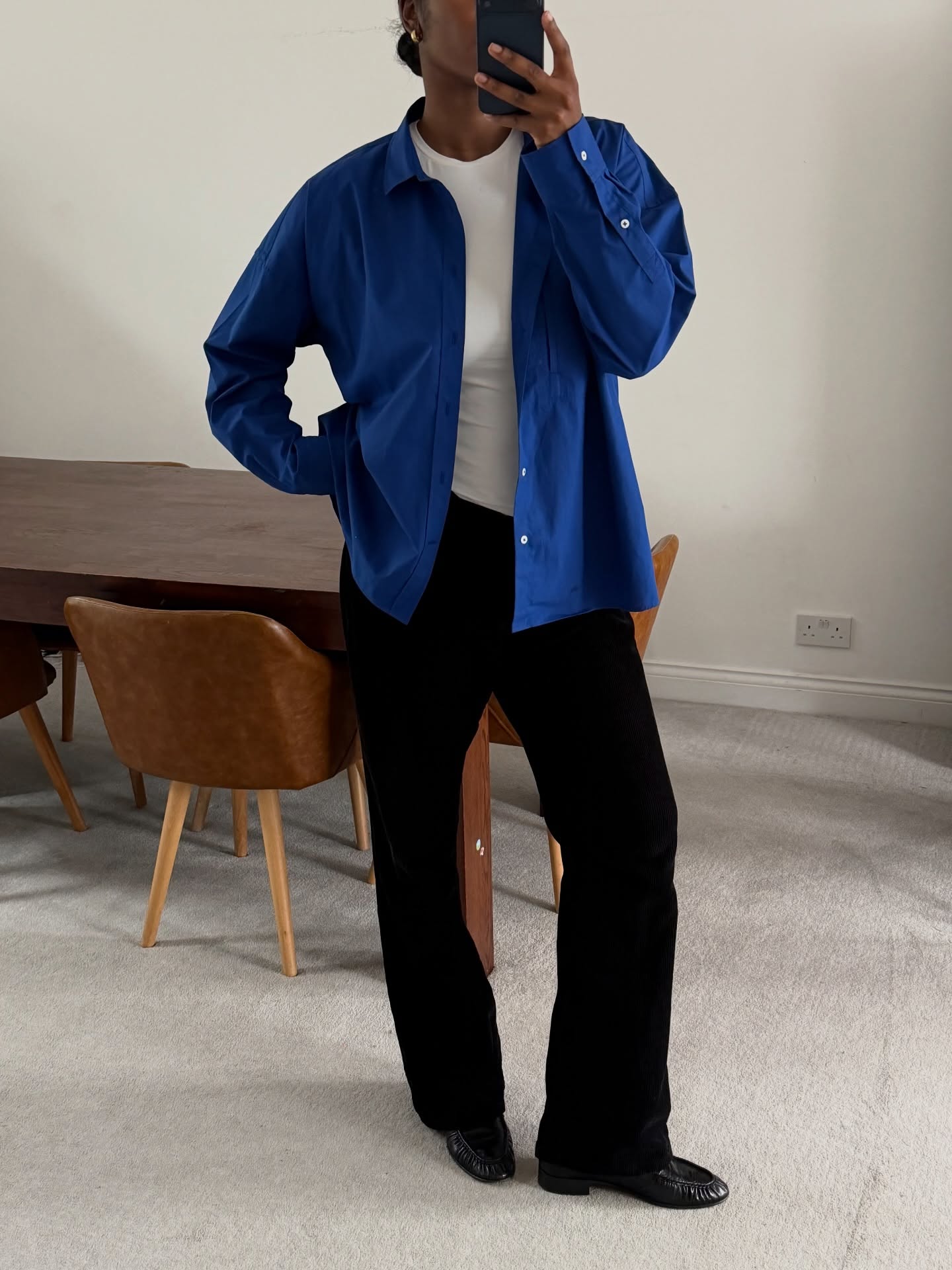 marilyn wears a blue shirt, white tee and black trousers london summer capsule wardrobe