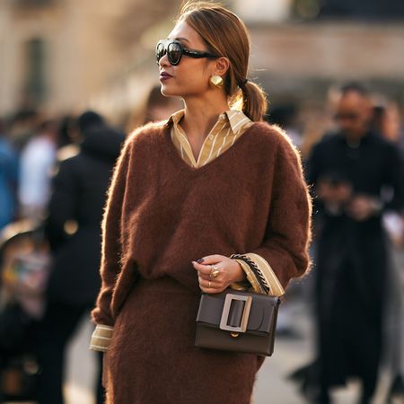 Fashion week attendee wearing sunglasses, ponytail, brown sweater and skirt 