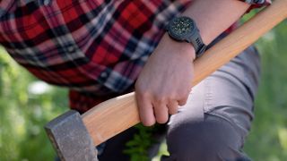 Man chopping wood wearing Garmin Instinct Crossover watch