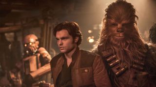 a man in the center is looking off into the distance, there is a large wookiee to his right, it looks like a large hairy bear cross ape. there is a robot with yellow eyes behind the man on the left of the image.