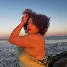 A woman standing in front of the sea at sunset
