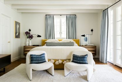 Yellow bedframe, wooden bedside tables, two white chairs