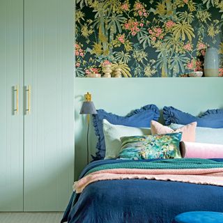 Pale green bedroom with blue bedding and wallpaper feature
