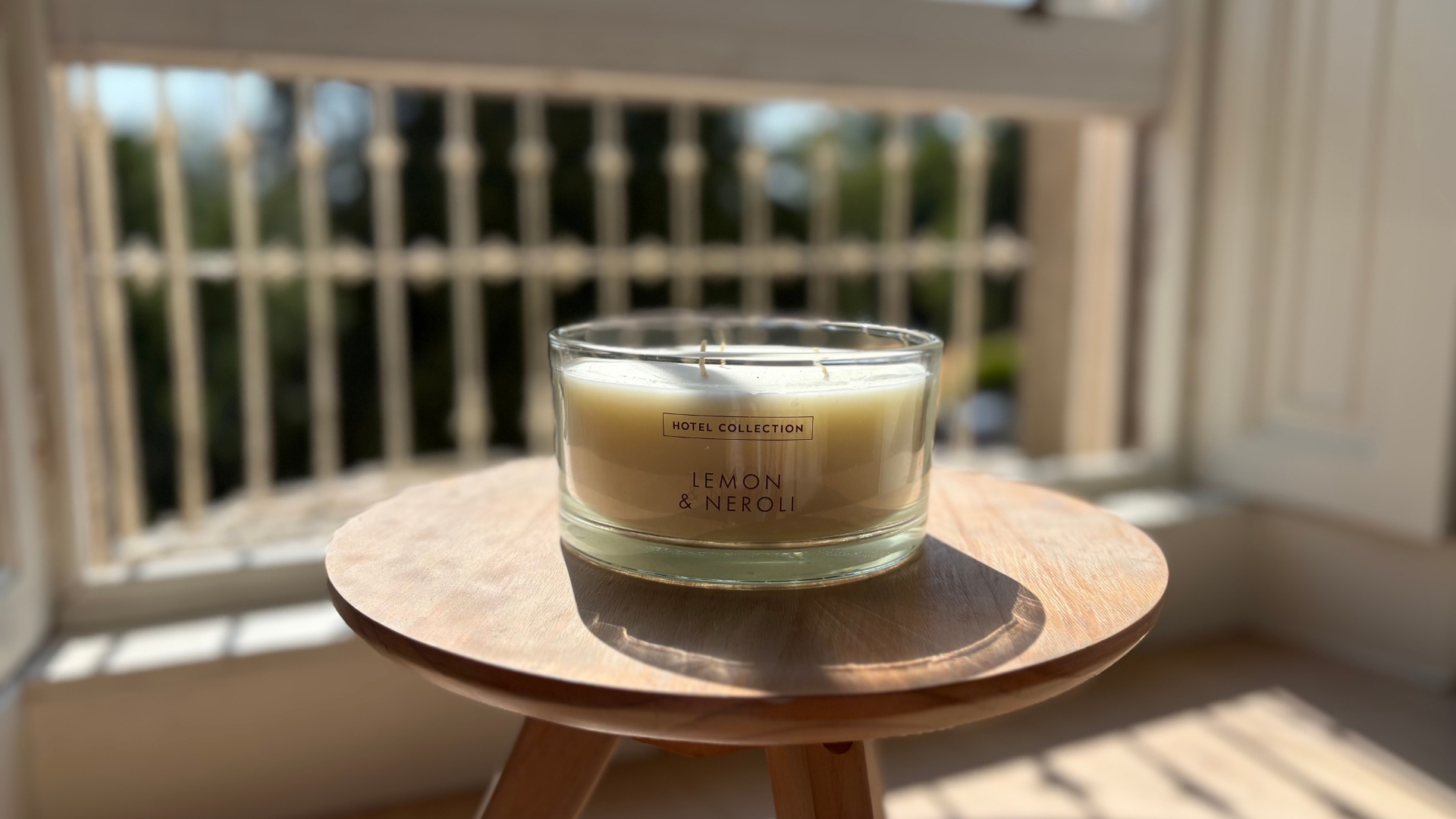 Aldi Lemon and Neroli Hotel Collection Triple Wick Candle on a wooden candle in front of a window