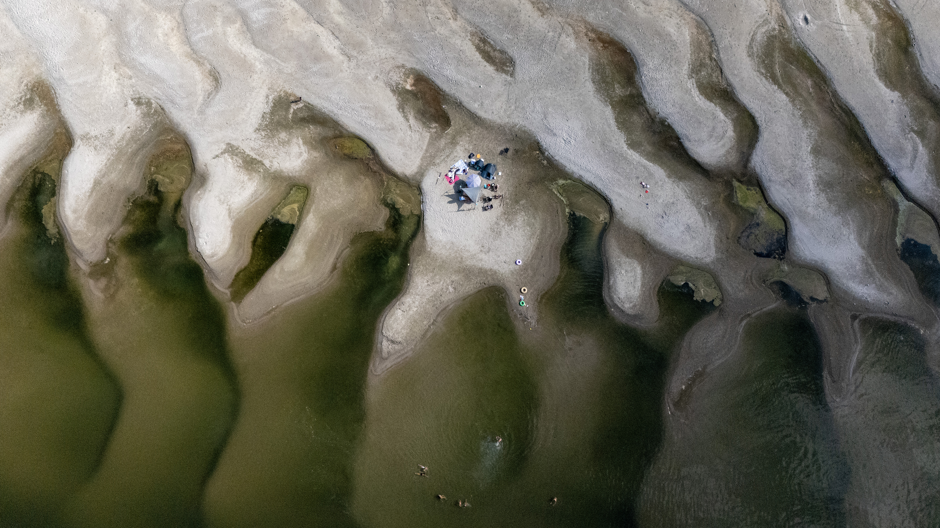 TOPSHOT - An aerial view shows a family with umbrellas on a sandbar uncovered by receding water on the Danube River near Ilok, Croatia, August 8, 2026. (Photo by MARKO PERKOV / AFP via Getty Images)