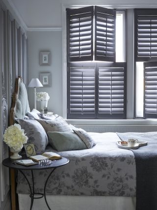 Gray bedroom with plantation shutters and botanical bedding.