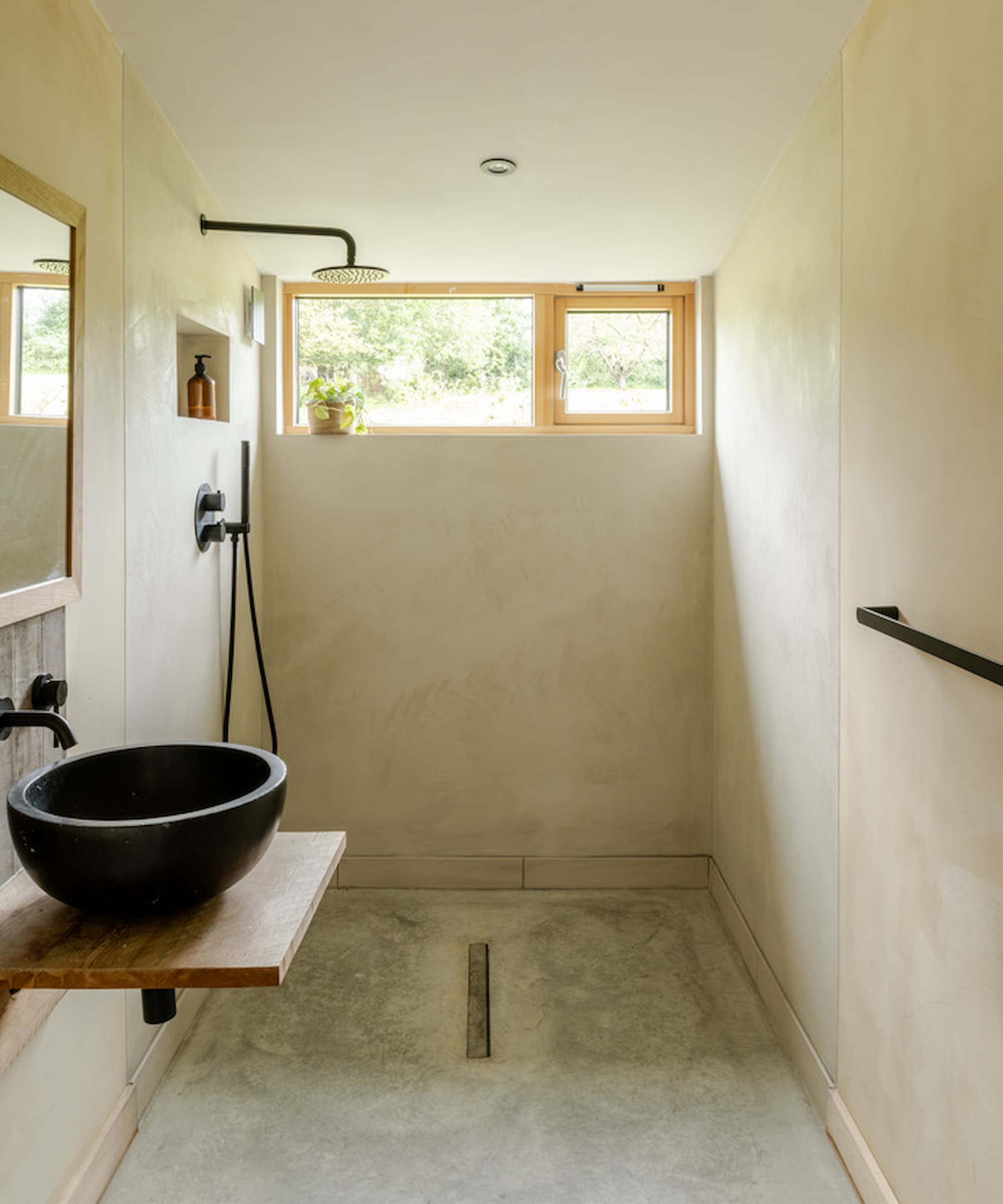 A bathroom with a open walk-in shower and black sink