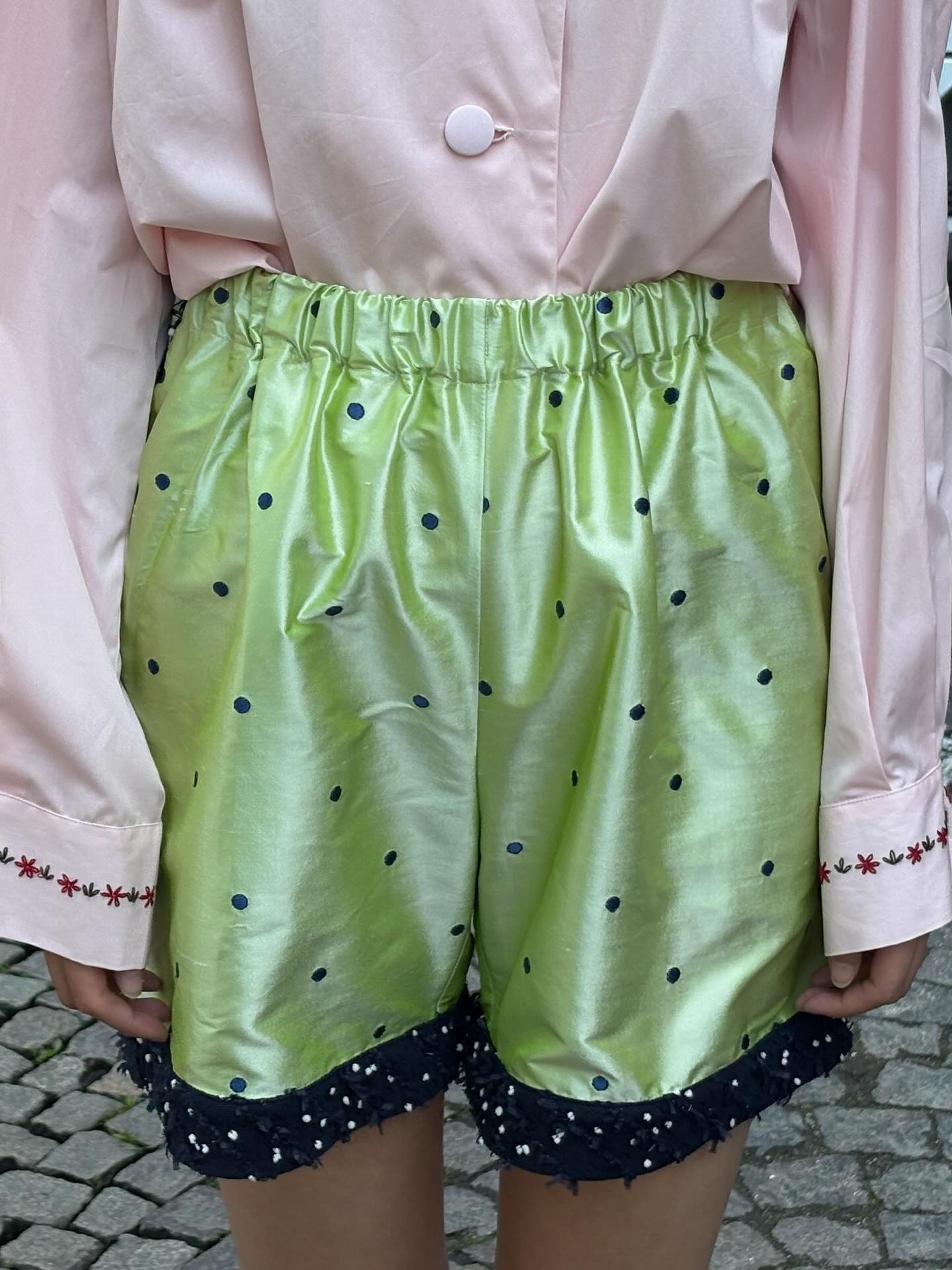 Model wearing pink shirt and patterned green shorts from Caro Editions.