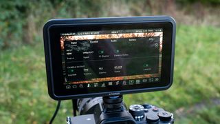 An Atomos Shinobi II camera monitor on top of a camera outside in a field