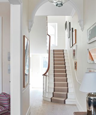 white hallway with staircase with neutral runner in London house