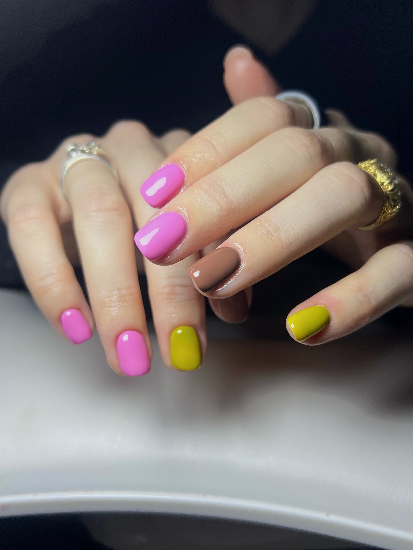 A manicure with pink, green and brown nail polish