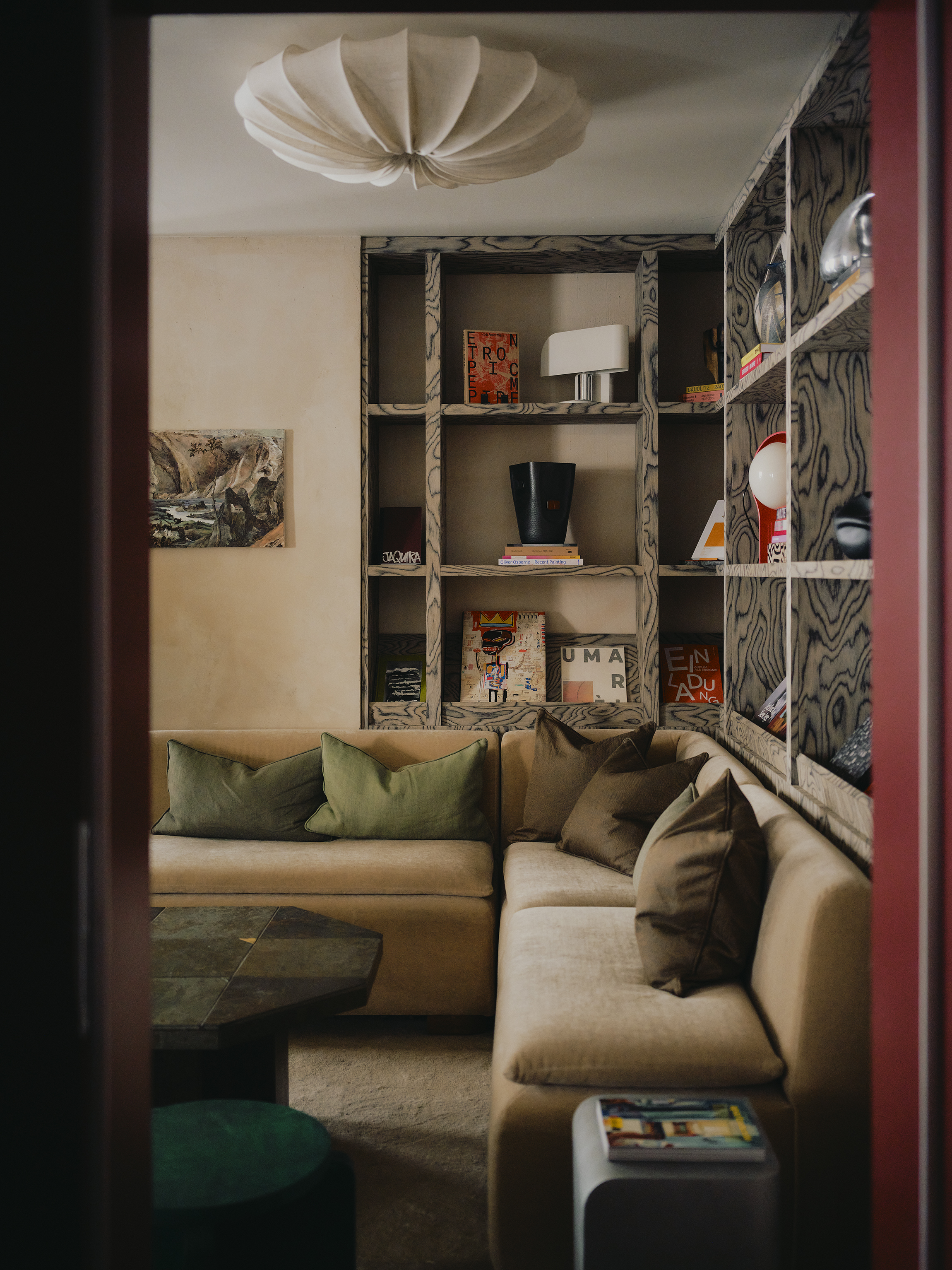 Interiors of a colorfully decorated hotel with a green, pink, and red palette, checkered or striped flooring, quirky, sculptural collectibles throughout, and lots of natural light.