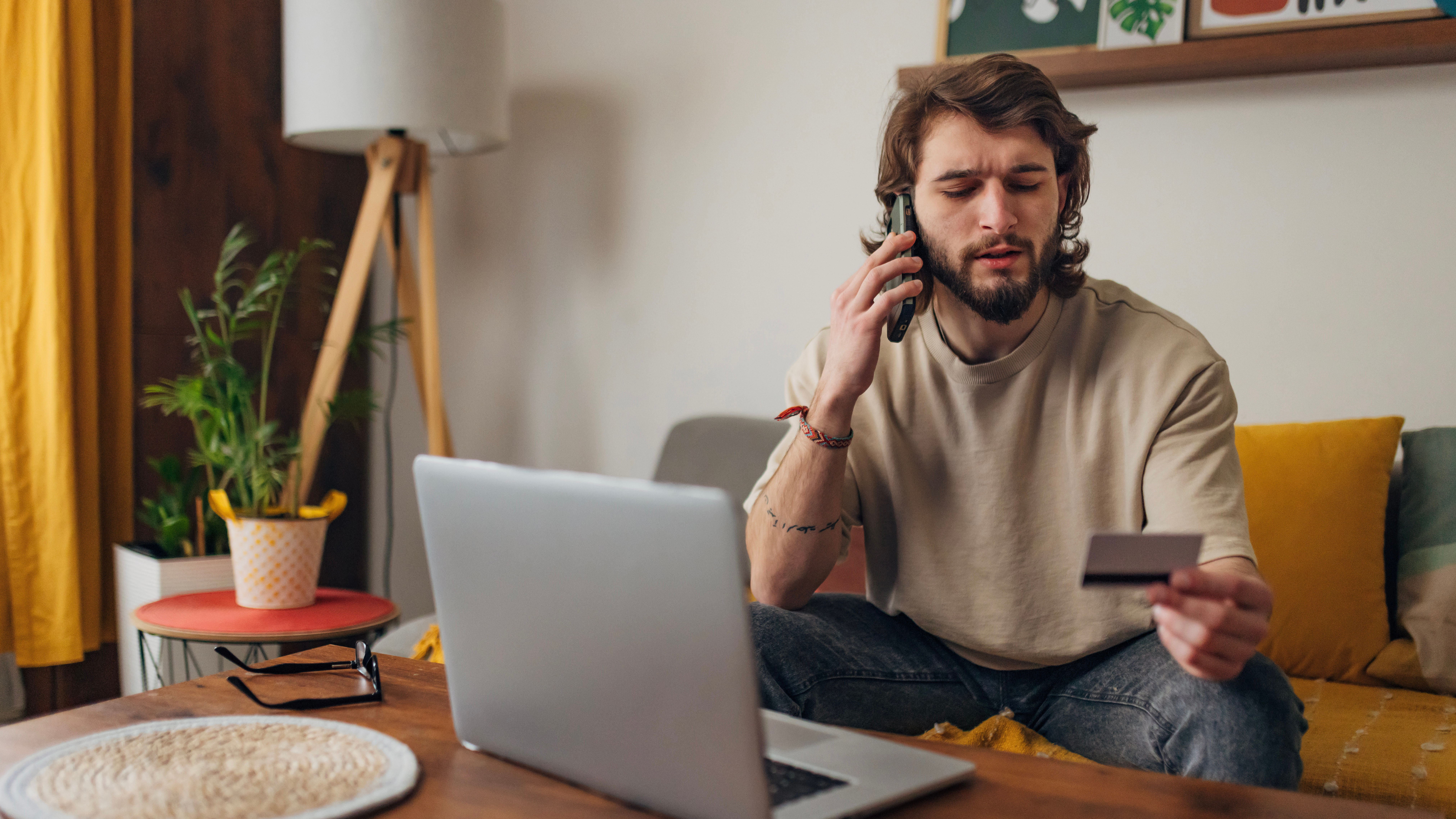 Man looking at credit card while on laptop