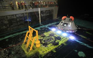 At night on Nov. 1, 2018, a test version of NASA's Orion space capsule is pulled into the well deck of the USS John P. Murtha during a recovery operations test in the Pacific Ocean.