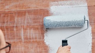 Women painting wood with a roller