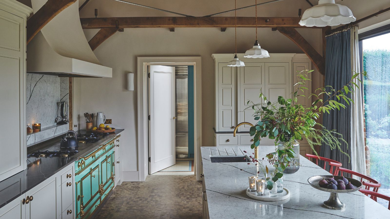 Modern fitted kitchen with an island, exposed beams under a pitched roof and large window