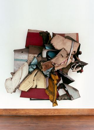 A crushed car sculpture is hung in the bedroom.