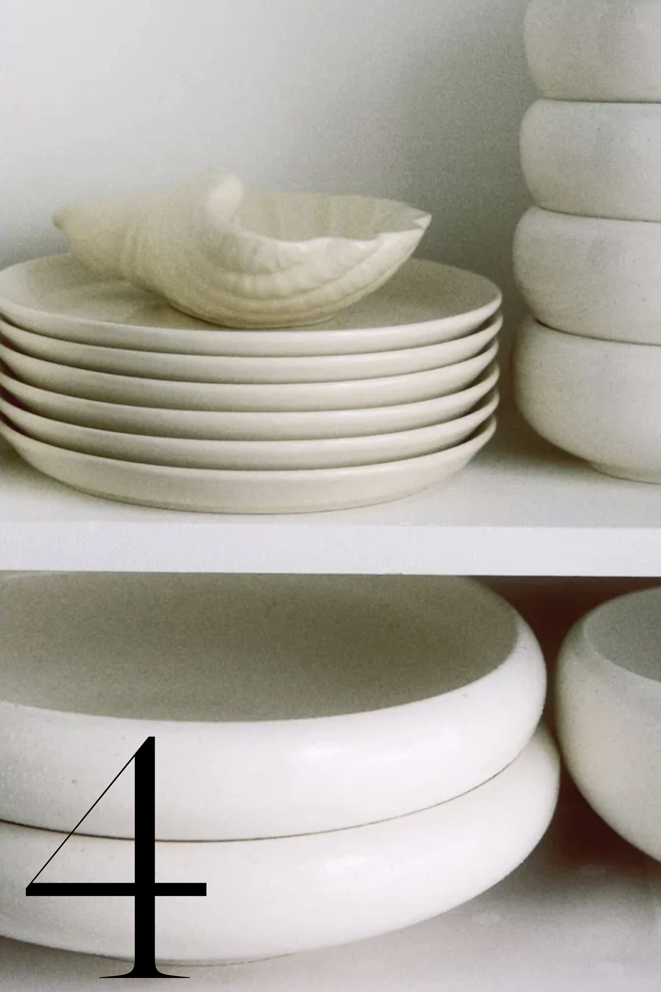stacked white plates on shelves with shell-shaped dish