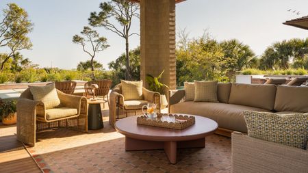 Outdoor living room with basket chairs, sofa and outdoor rug in an earthy palette